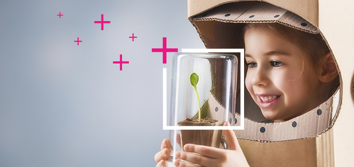 Glad flicka ser med framtidshopp på en liten planta
